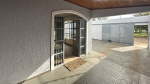 A covered outdoor area with a wooden ceiling, a tiled floor, and a metal gate leading to a covered entrance. - Pousada Residencial - Atrás Shopping pvh (Porto Velho)