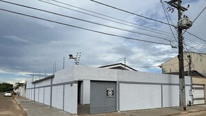 A building with a grey exterior, a gated entrance, and multiple utility poles with wires. - Pousada Residencial - Atrás Shopping pvh (Porto Velho)