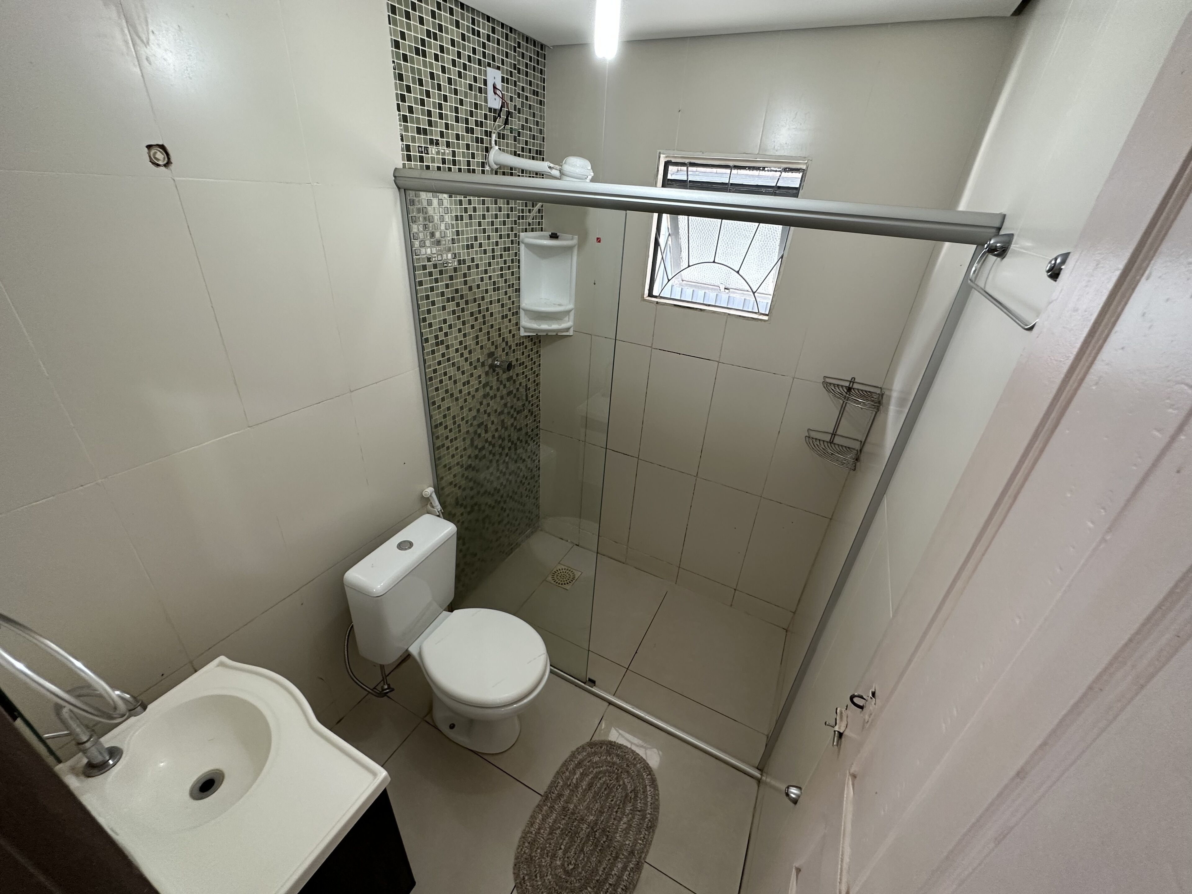 A small bathroom with a toilet, sink, and shower stall.