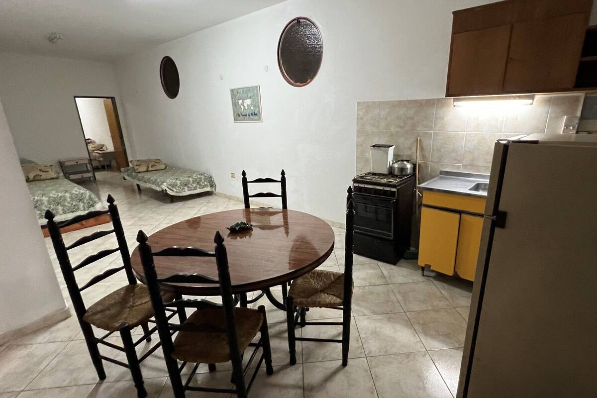 A compact kitchen with a dining table, chairs, a refrigerator, a stove, and a sink.