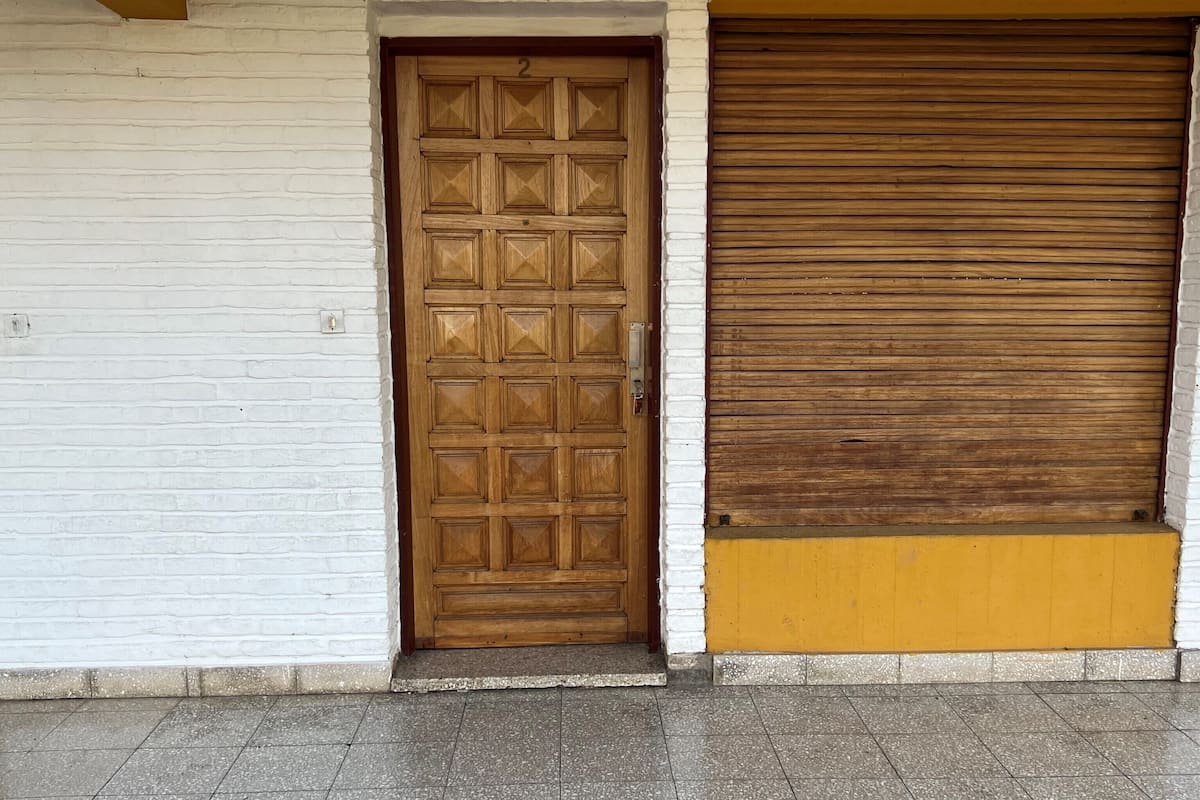 A closed wooden door with a metal handle and a shutter door to the right.