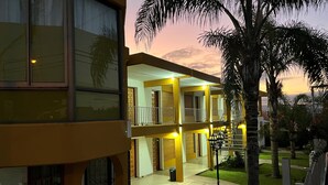 Un edificio de varios pisos con balcones, un espacio al aire libre cubierto y vistas al atardecer.