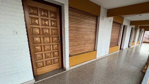Un pasillo con puertas de madera cerradas y suelo de baldosas.
