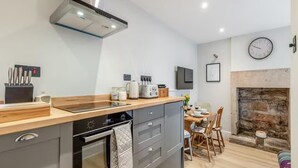 Une cuisine moderne dotée d’un îlot central, d’un four encastré et d’une cheminée en pierre.