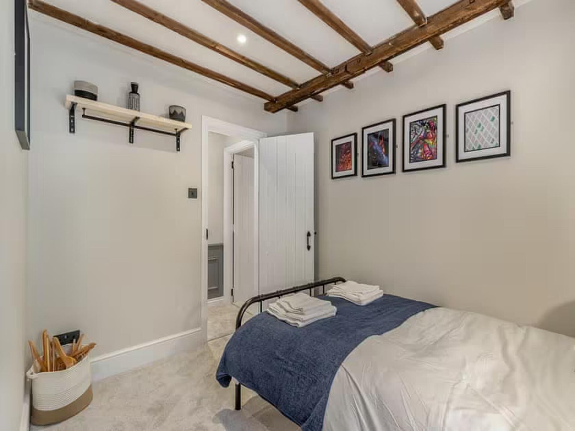 Ein Schlafzimmer mit einem Bett, Holzboden, einer Tür und gerahmten Kunstwerken an der Wand.