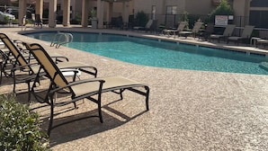 Un espace piscine avec des chaises longues et un bâtiment doté d’un toit en tuiles.
