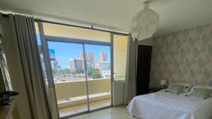 Habitación de hotel con cama, escritorio, silla y vistas amplias de la ciudad.