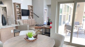 Ein modernes Wohnzimmer mit einem runden Holztisch, beigen Sofas und einem flachbildfernseher an der Wand.