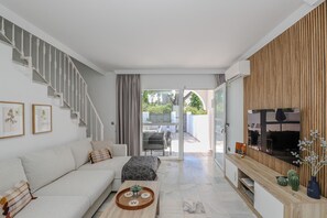Een moderne woonkamer met een trap, een bank, een salontafel en een televisie.