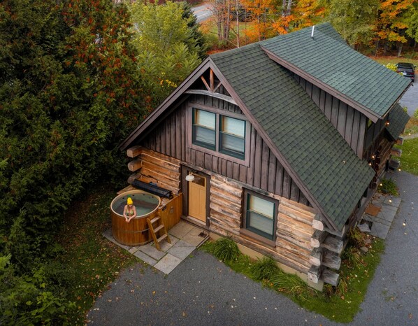 Une cabane avec une façade en bois, un jacuzzi et un garage.