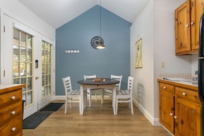 A dining area with a round table and four chairs, a clock on the wall, and wooden cabinets. - Cozy wooded mountain retreat 10 minutes from downtown Asheville (Asheville)