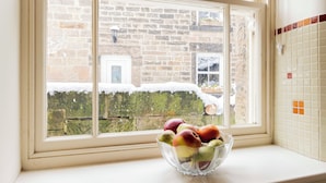 A clear glass bowl with apples on a windowsill.