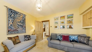 A living room with two grey sofas, a wooden bench, a large tapestry, and framed pictures on the wall.
