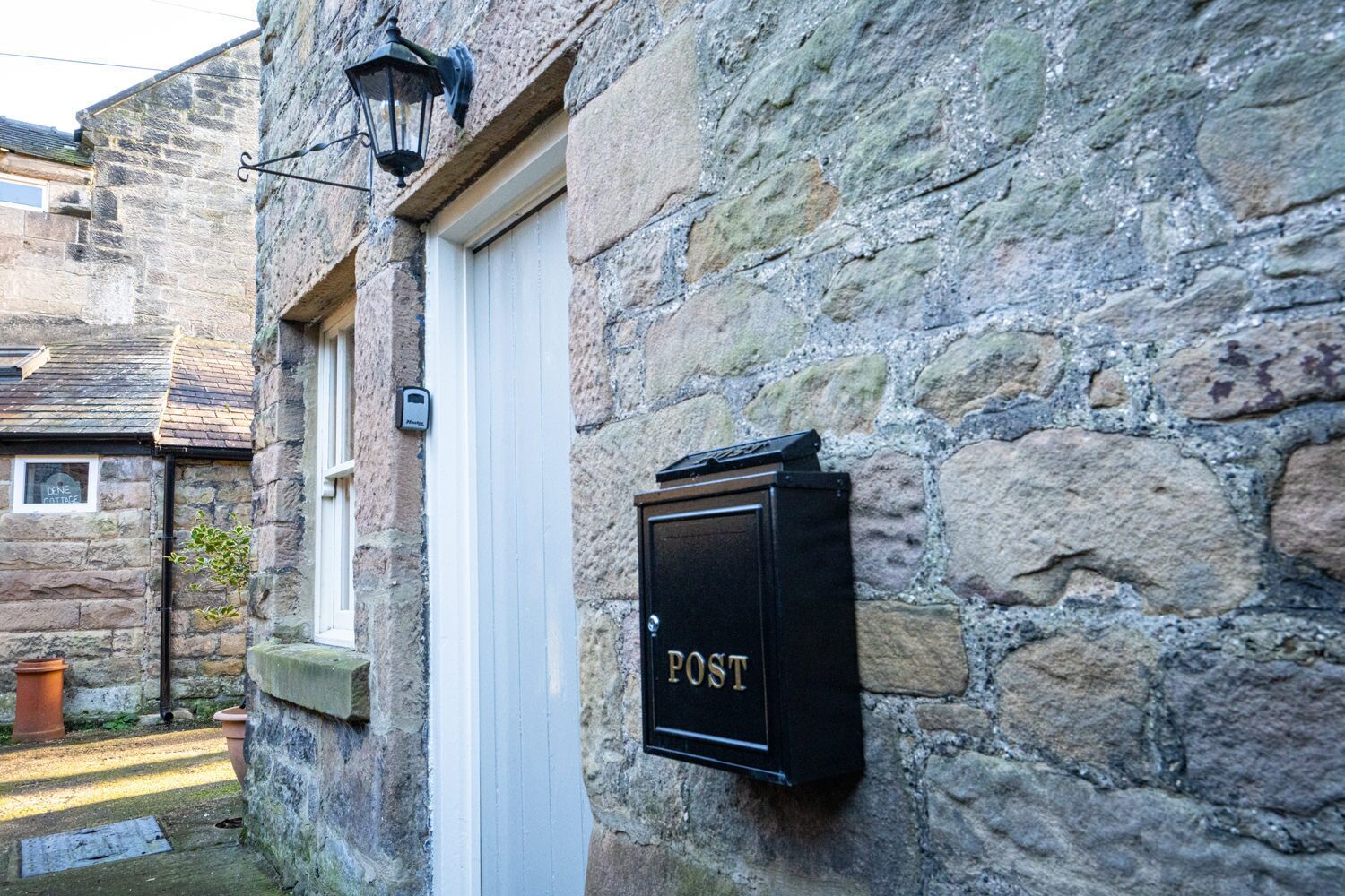 A stone building with a mailbox labeled "POST" and a door.