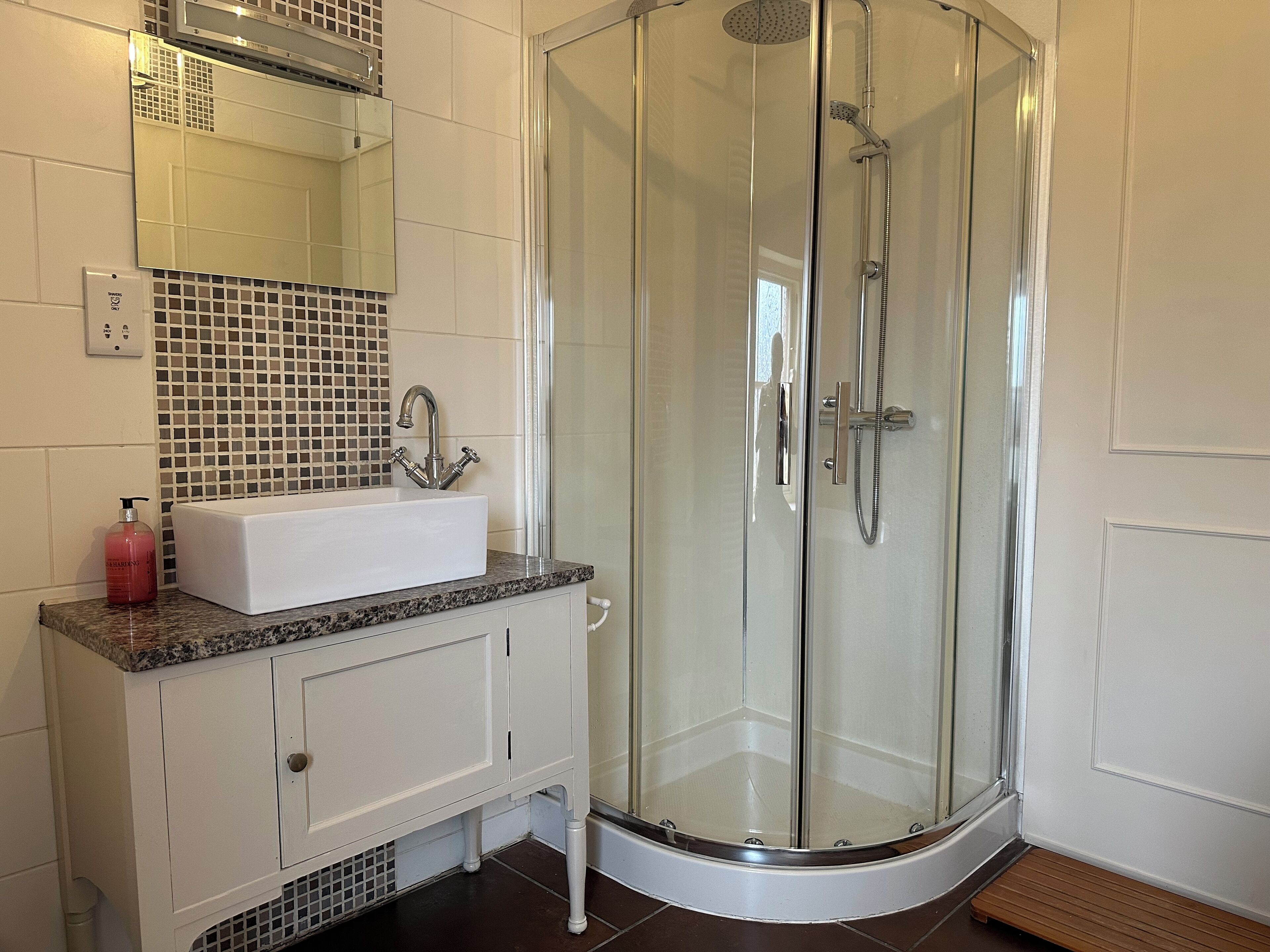 A modern bathroom with a glass-enclosed shower, a white sink with a marble countertop, and a tiled backsplash.