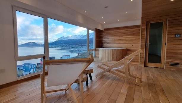 Ein geräumiges Zimmer mit großen Fenstern und Blick auf Berge und einen See.