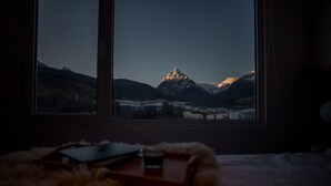 Ein Zimmer mit Bett, Fenster und Bergblick.