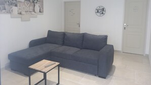 Een moderne woonkamer met een grijze bank, een klein houten tafeltje en een decoratie aan de muur.
