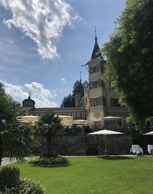A historic building with a tower and a dome, surrounded by a well-maintained garden with palm trees and flowers. - Schönes Appartment Nähe Hafen Kreuzlingen (Kreuzlingen)