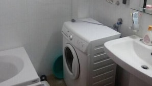 A compact bathroom with a toilet, washing machine, and sink.