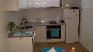 A compact kitchen with white cabinets, a sink, a stove, and a refrigerator.