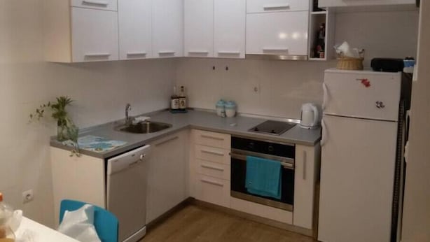 A compact kitchen with white cabinets, a dishwasher, an oven, and a refrigerator.