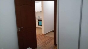A narrow hallway with a wooden door leading to a kitchen area.