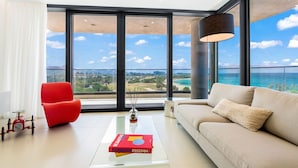 A modern living room with a red chair, beige sofa, and a book titled "STANDING FREEDOM" on a glass coffee table. - 602- Stunning one bedroom oceanview (Cupecoy)