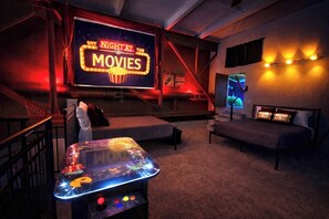 A cozy movie theater with a large screen, comfortable seating, and a retro arcade machine.