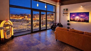 Ein Zimmer mit großem Fenster, einer Jukebox, einem Sofa und einem Wandbild.