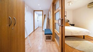 Una habitación de hotel con una cama, un escritorio pequeño, una silla y un armario de madera.