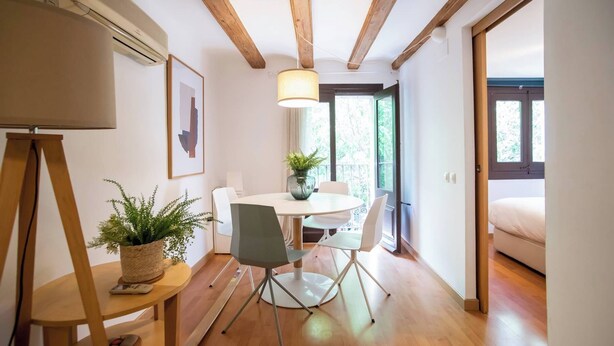 Un comedor moderno con una mesa redonda, sillas y una planta en maceta.