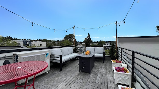 A rooftop terrace with a sofa set, a red table, and a flower arrangement. - Downtown Ballard View Home Walk to Bars & Shops (Seattle)