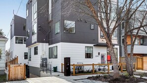 A modern multi-story residential building with a flat roof, large windows, and a visible garage door. - Downtown Ballard View Home Walk to Bars & Shops (Seattle)