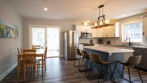 Una cucina moderna con isola centrale, sgabelli da bar e zona pranzo con sedie in legno.