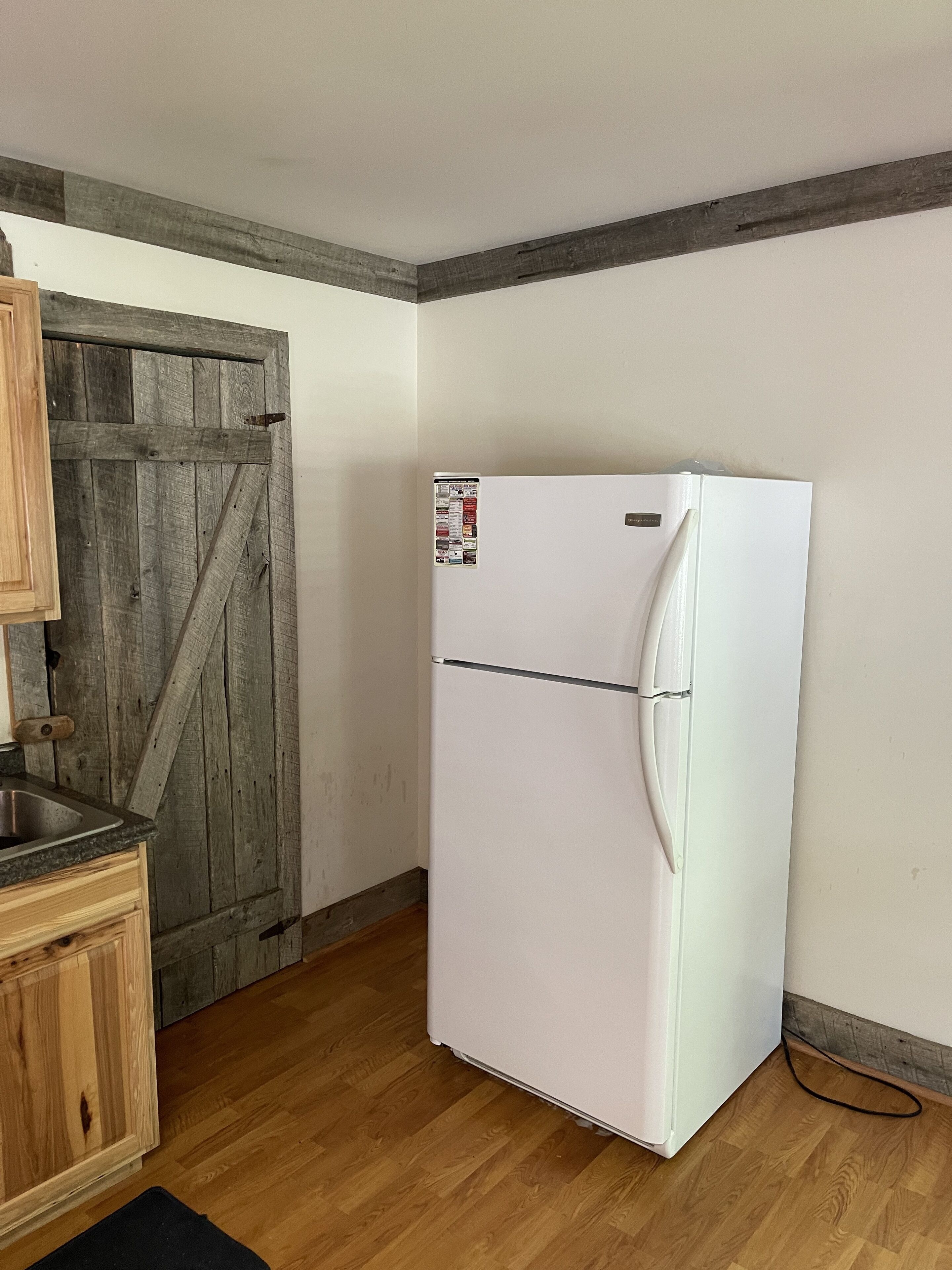 A kitchen with a white refrigerator, wooden cabinets, and a wooden door.