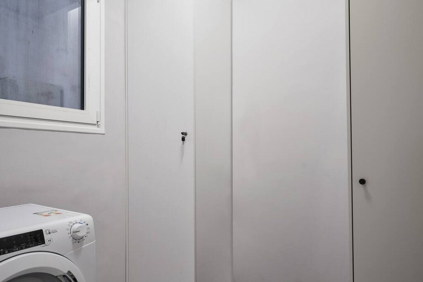 A laundry area with a washing machine and two white doors.