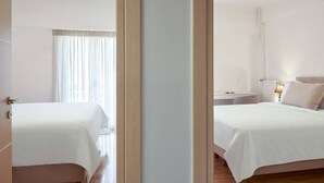 A hotel room with two beds, a bedside table with a lamp, and a window with curtains. - Fix  · Fix 2bd apartment with Parthenon view (Athina)