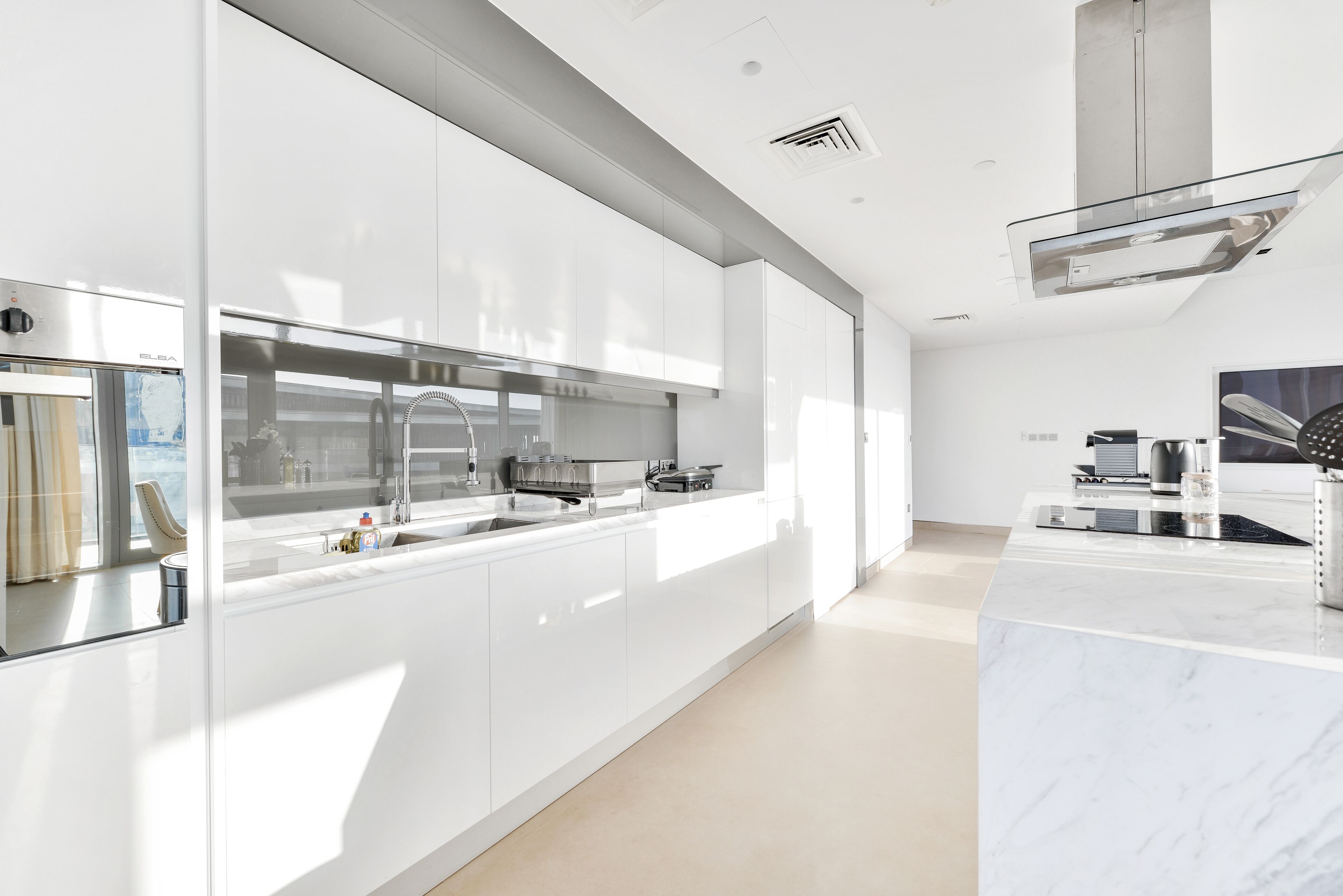 A modern kitchen with white cabinetry, stainless steel appliances, and a marble countertop.