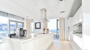 Eine moderne Küche mit Marmorarbeitsplatte, Edelstahlgeräten und einem großen Fenster mit Blick auf die Stadt.