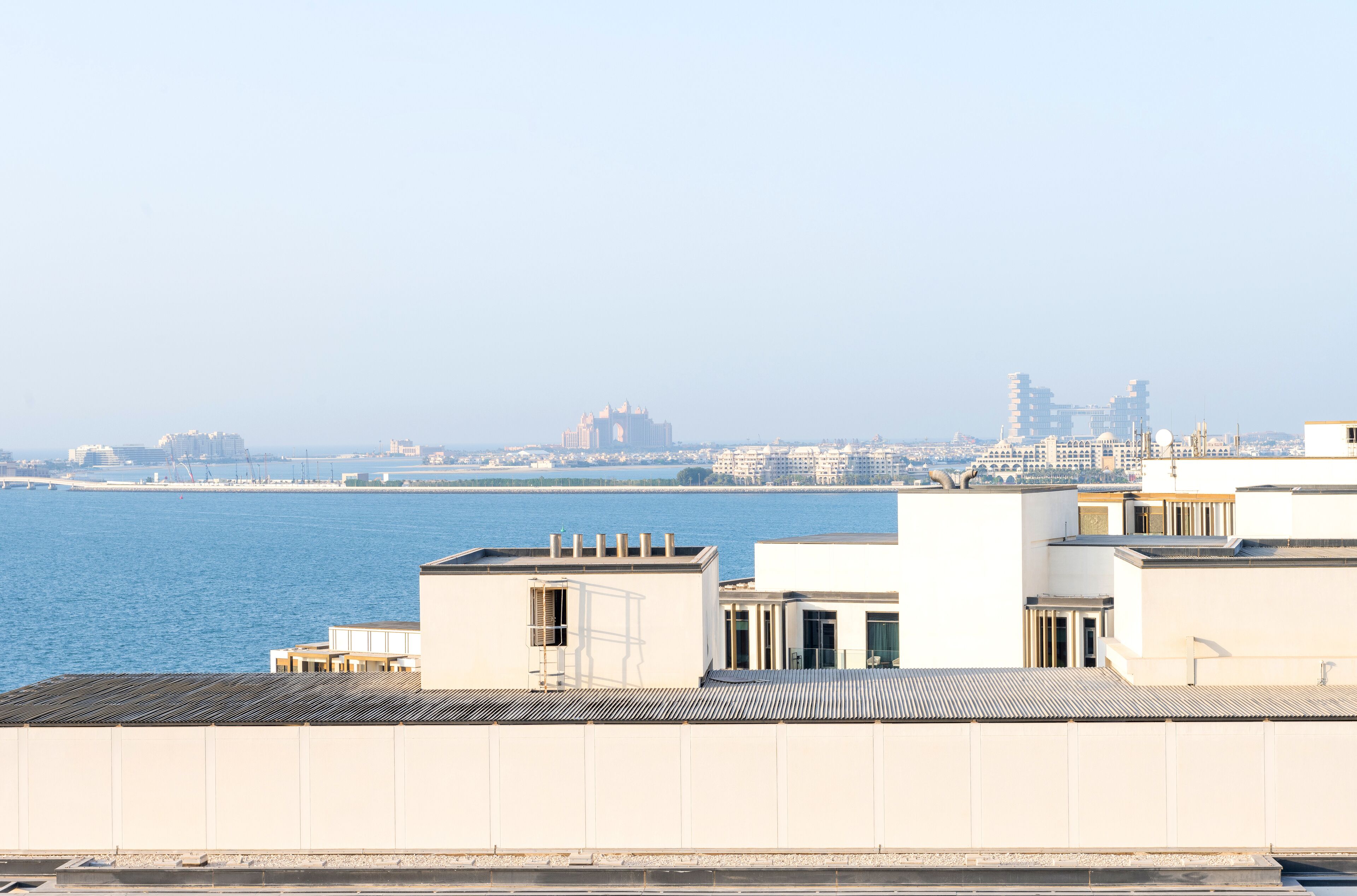 A high-rise building with a view of the water and distant cityscape.