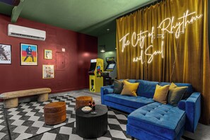 Ein Zimmer mit einem blauen Sofa, einer Bank, einem runden Couchtisch und einem Neon-Schild mit der Aufschrift 'The City of Rhythm and Soul'.