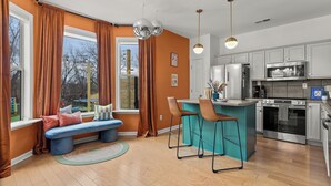 Een moderne keuken met een centraal eiland, barkrukken en een ingebouwde oven.