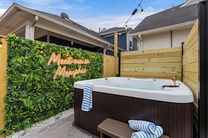 Een hottub met een houten bankje en een bankje met blauw-witte streepkussens.