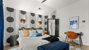 Een moderne slaapkamer met een bed, nachtkastje en bureau met stoel.