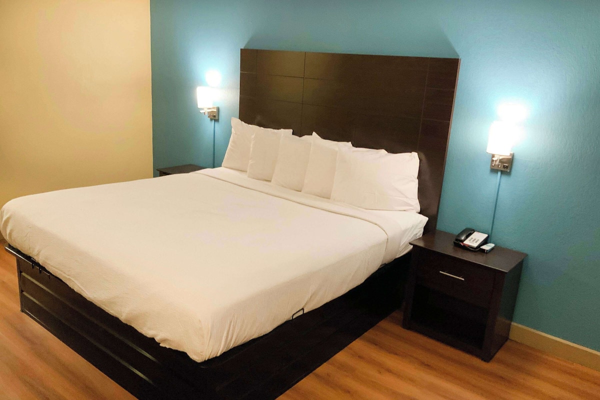 Une chambre d’hôtel avec un grand lit, une table de chevet avec un téléphone et des lampes fixées au mur.