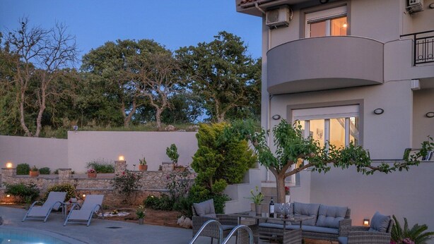 A two-story house with a swimming pool, outdoor furniture, and a landscaped garden. - Villa Hercules | Refreshing Pool & Hydromassage (Rethymno)