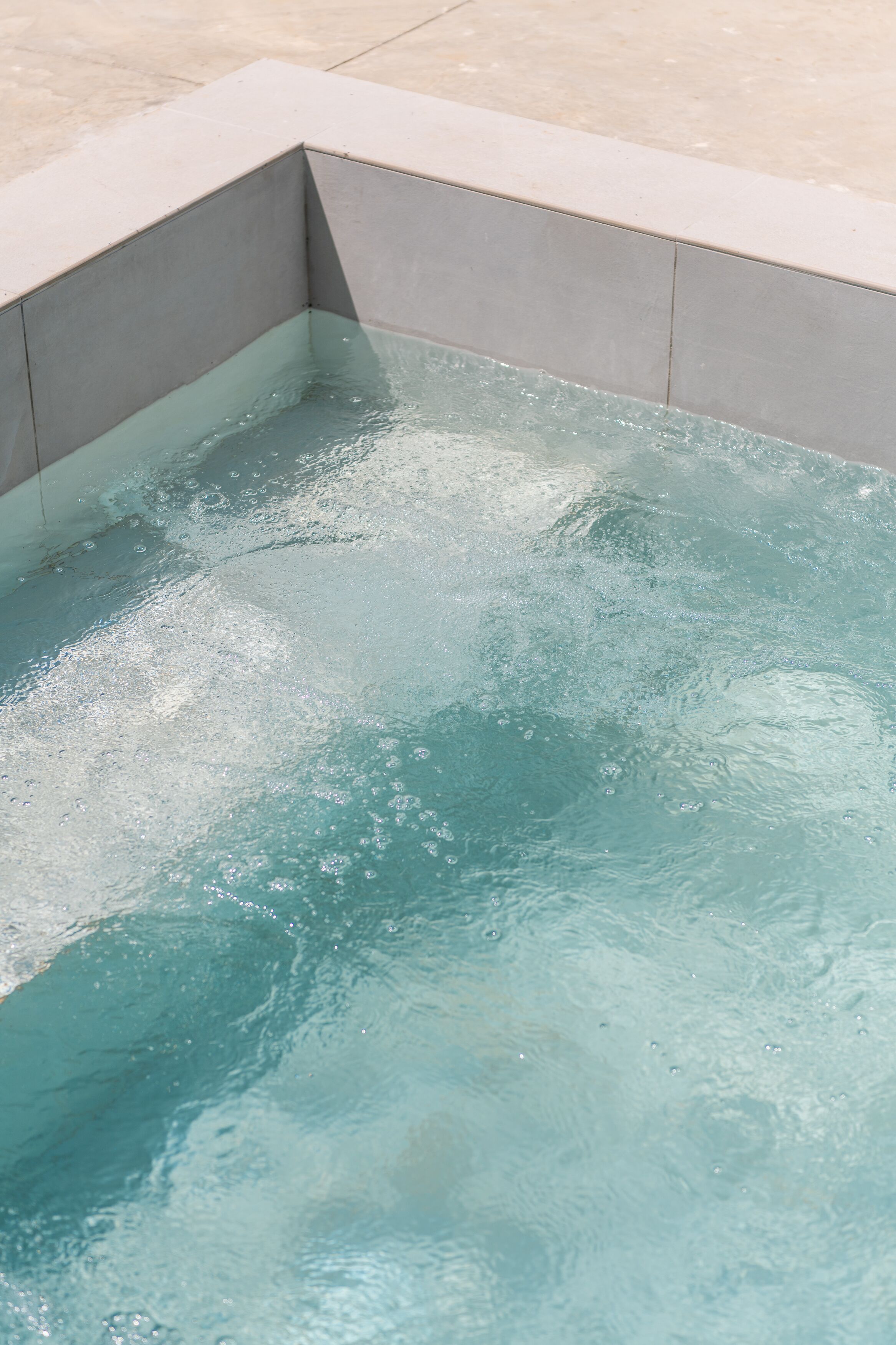 Une piscine rectangulaire à l’eau claire, bordée d’un revêtement de carrelage.