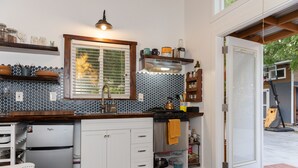 Een moderne keuken met witte kasten, een roestvrijstalen koelkast en een raam met zonwering.