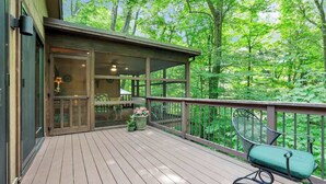 A wooden deck with a glass door leading to a room, surrounded by a forest. - Salt Run Retreat| Trails, Decks, & Screened Porch (Granville)
